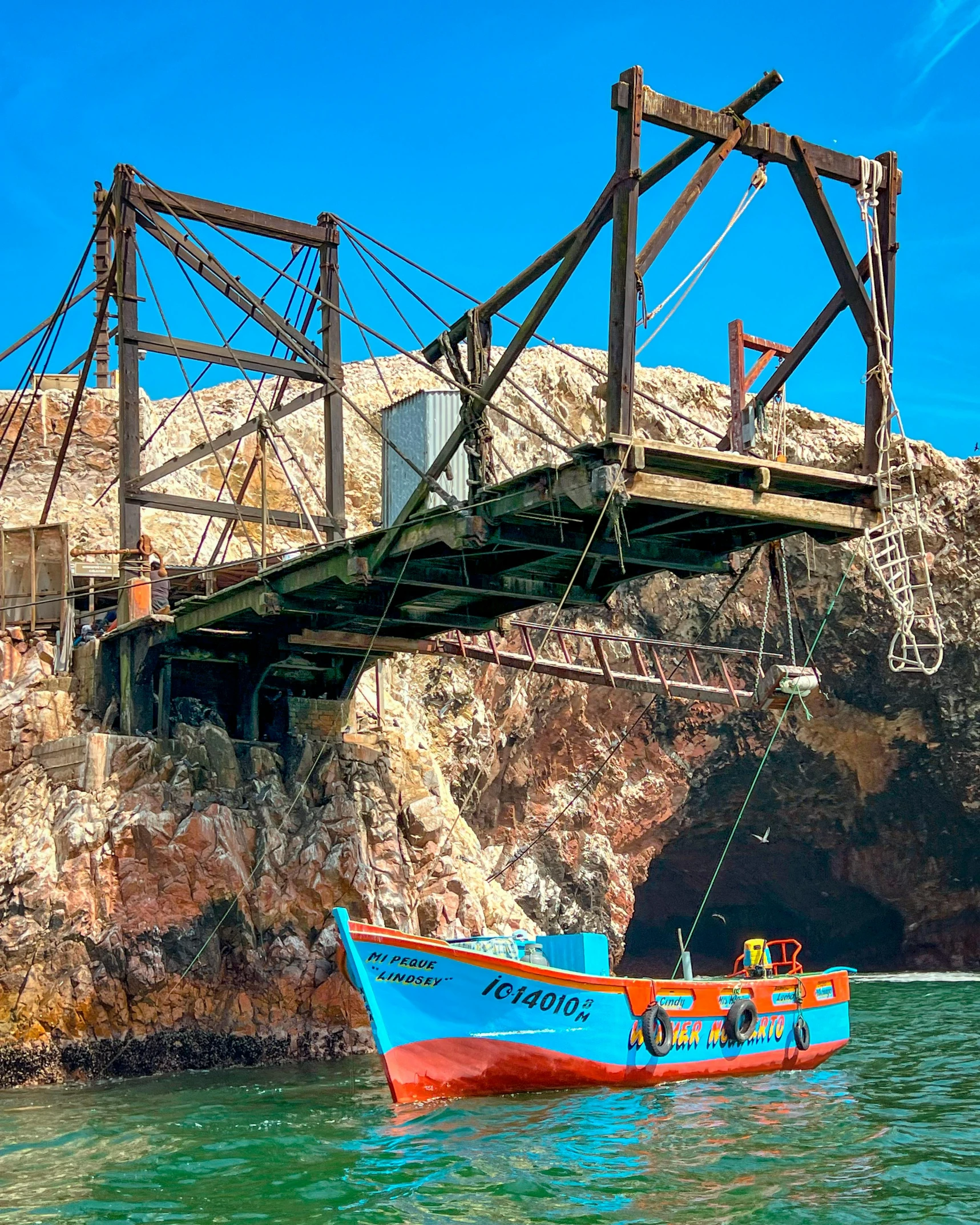 a boat pulling up passengers in front of a cave