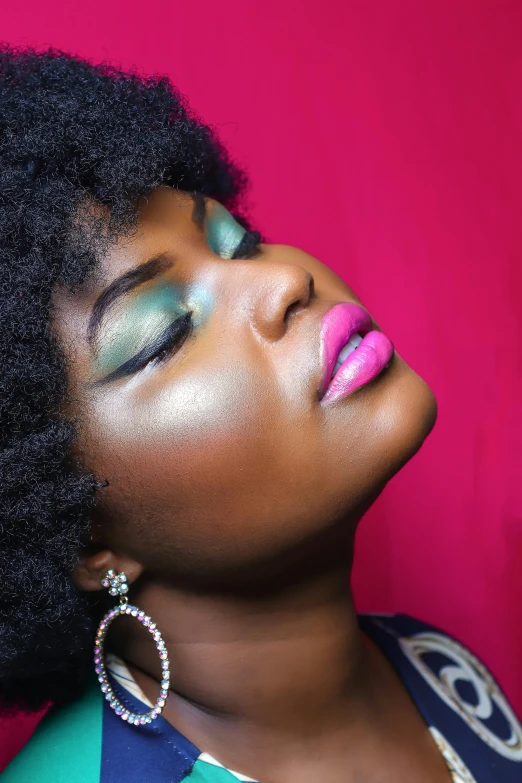 a woman with bright makeup on and a pink background