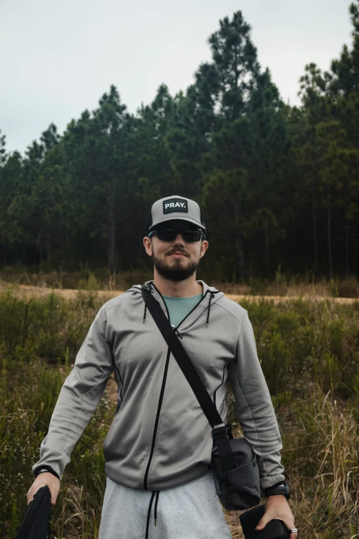 man standing in grass wearing glasses and a cap