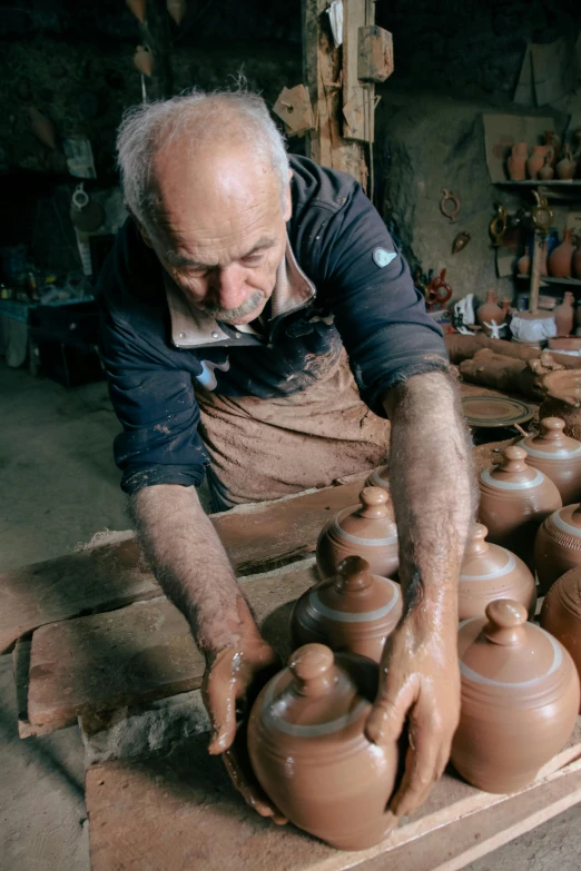 a man with gloves on, placing a pot on a table