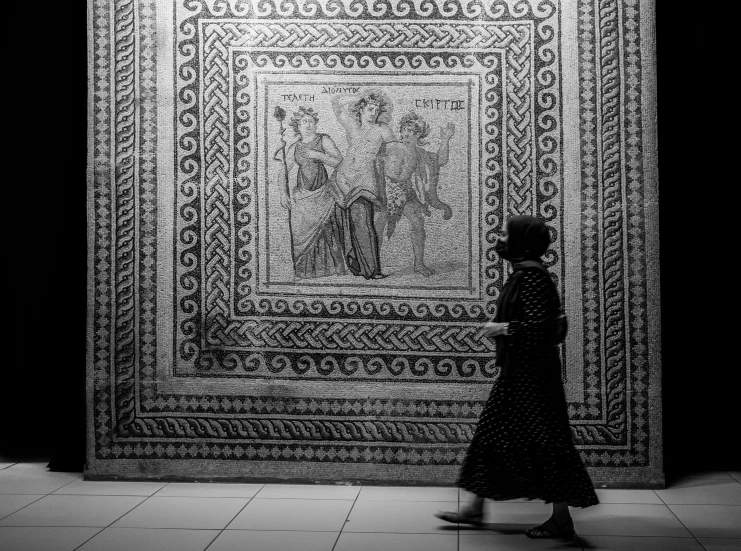 a black and white po of woman walking past rugs