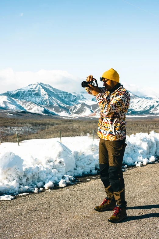 a man standing outside in front of snow covered mountains