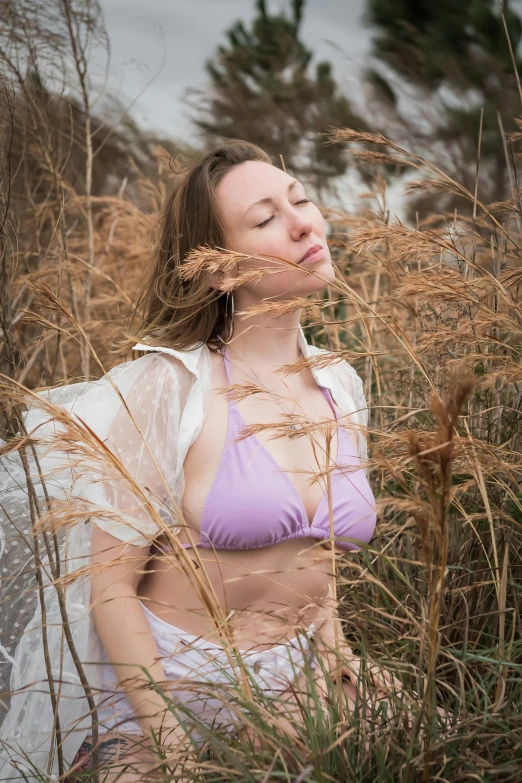 a women is posing in a field with tall grass