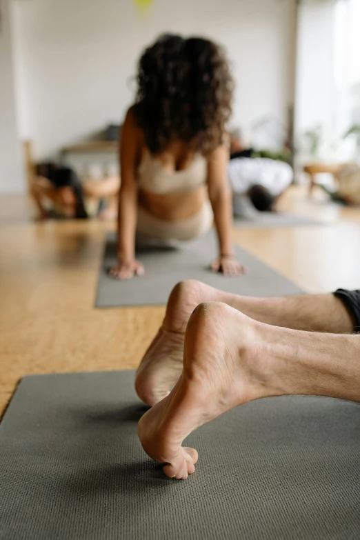 two people doing yoga on grey mats in a room