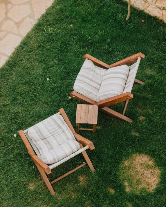 two reclining chairs that are on the ground in the grass