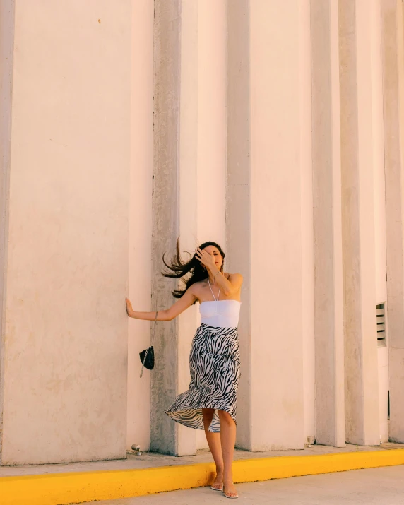 woman holding back against wall with her long hair