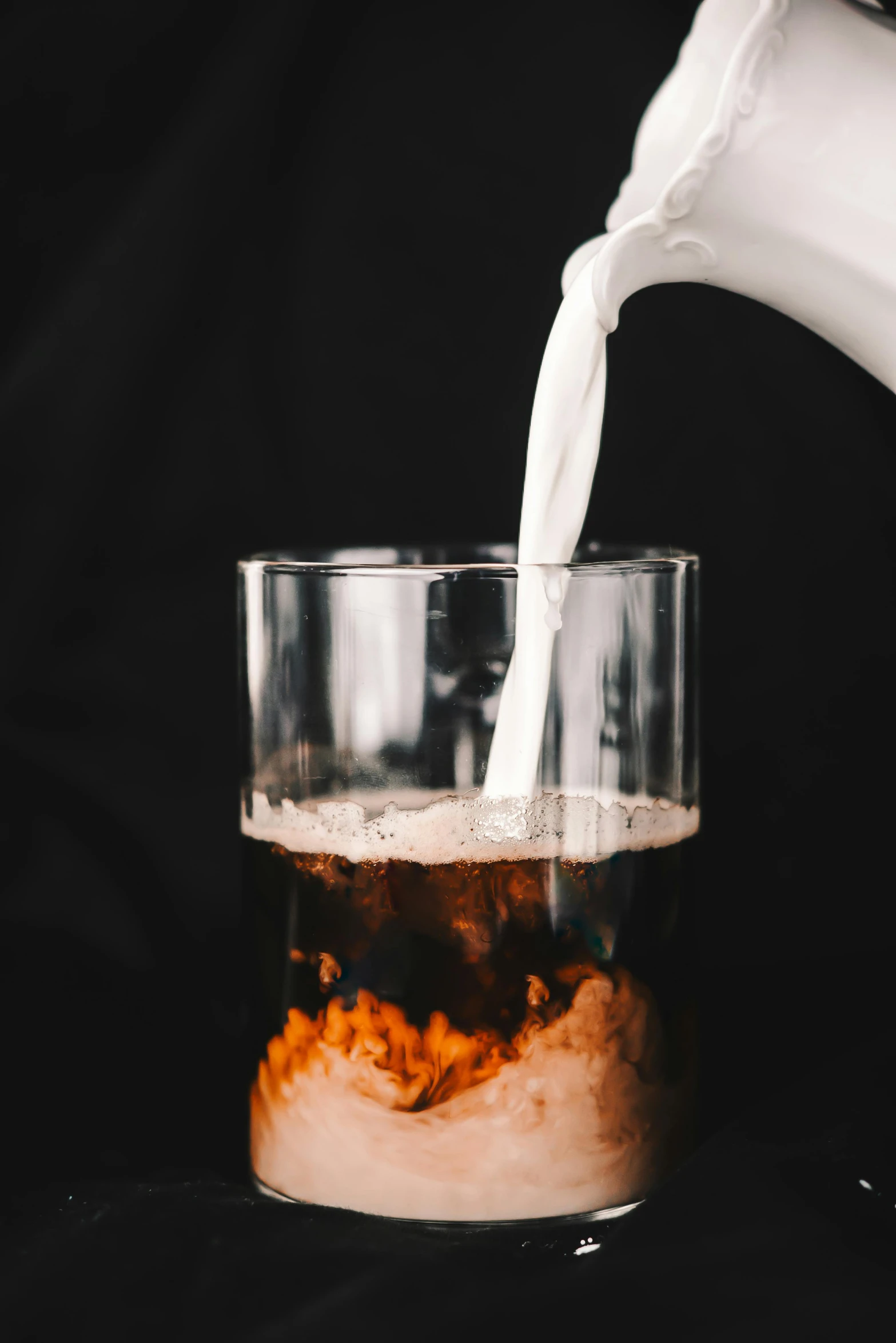 a cup filled with liquid and a white milk poured in it