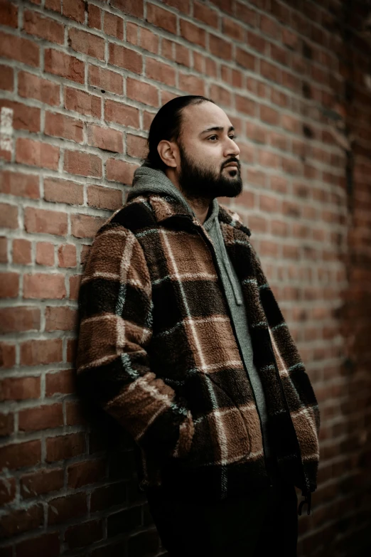 a man leaning against a wall and looking away from the camera