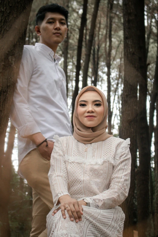 an attractive woman in a hijab standing next to a man