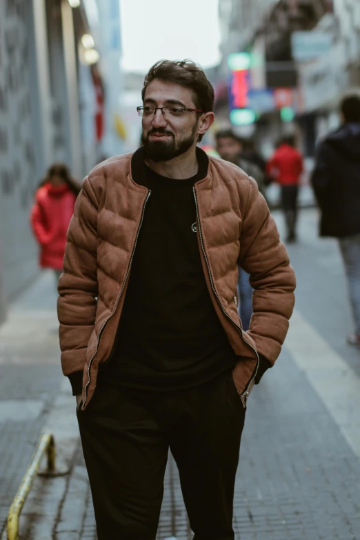 a man walking down the sidewalk while wearing a jacket