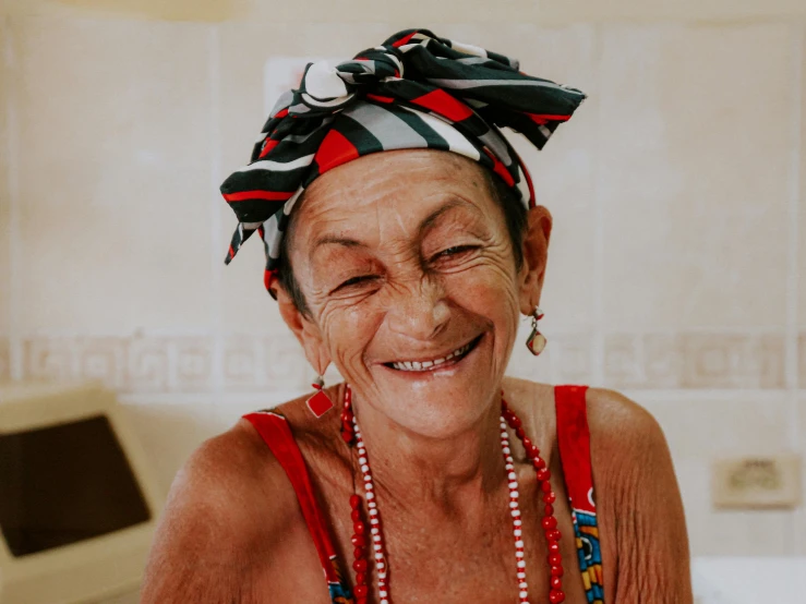 an older woman with colorful earrings wearing a scarf and beads