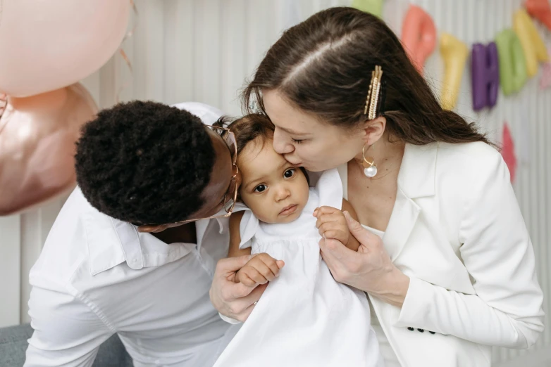 a woman with a man and a baby are in front of balloons