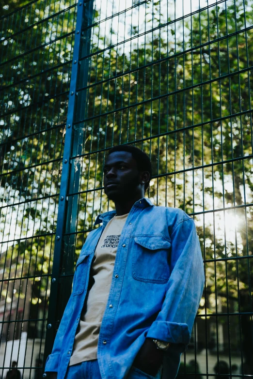 a man poses for a portrait near a fence