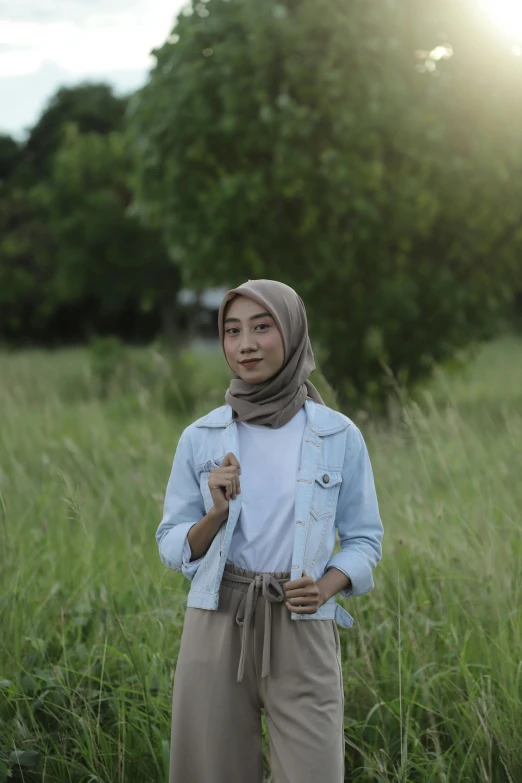 the woman is wearing a hijab standing in tall grass