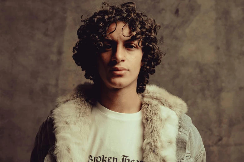 a man with long curly hair wearing a white t - shirt