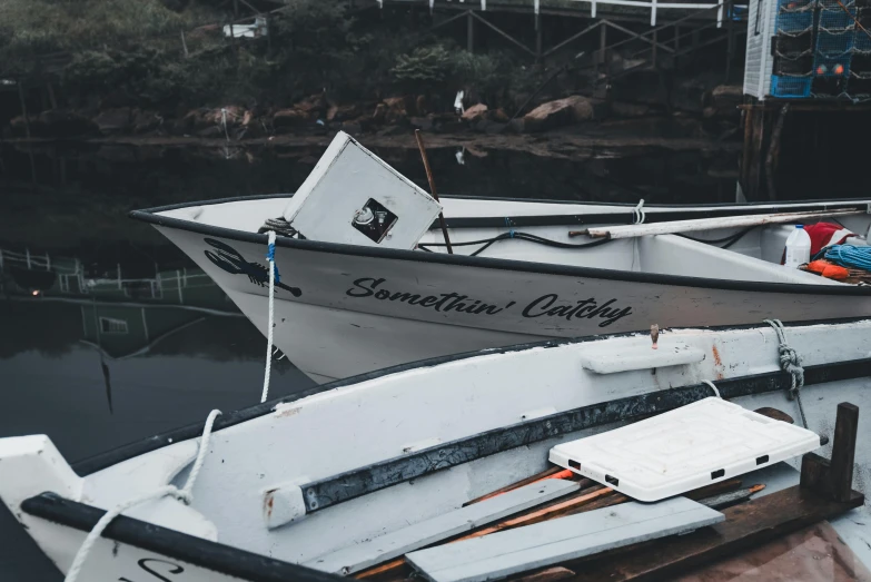 a white boat with a person on the front of it sitting next to another boats