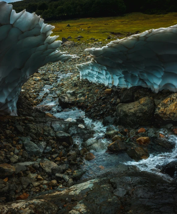 a stream of water running under ice that flows over some rocks