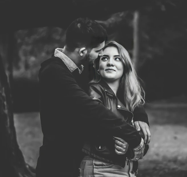 the young man and woman are hugging each other