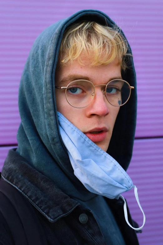 a man with glasses and an over head blue scarf