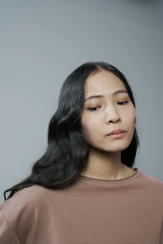 a woman with long black hair stands looking at soing