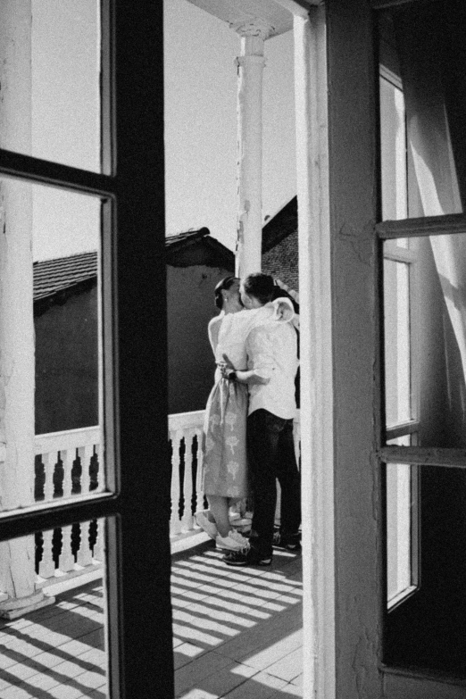 two people emcing on the deck near a window