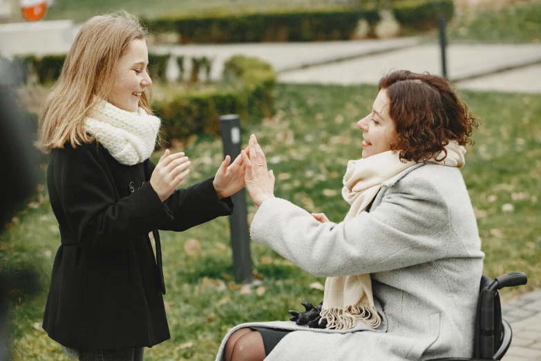two woman in black jackets and scarfs talk to each other
