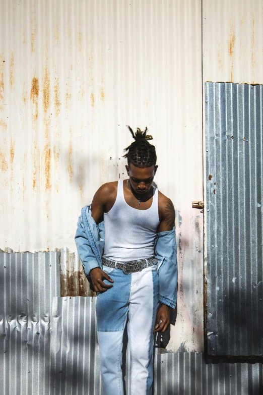 a man wearing jeans and jeans pants standing by a building