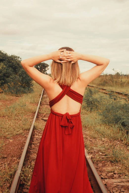 a woman with her back turned looking towards the train tracks