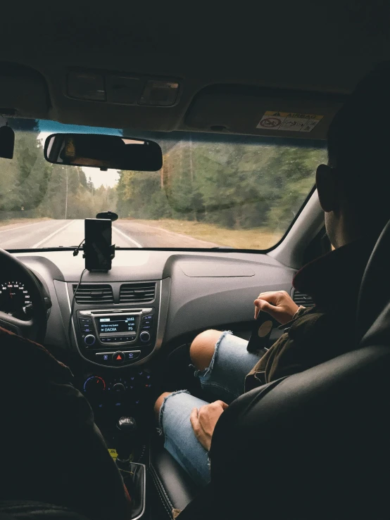 people are driving in their cars, the driver is adjusting his radio