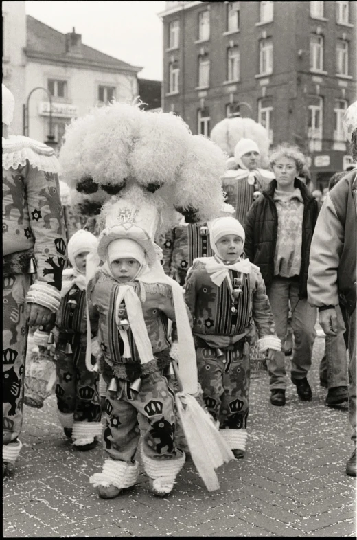 many children walking down a street dressed in costumes