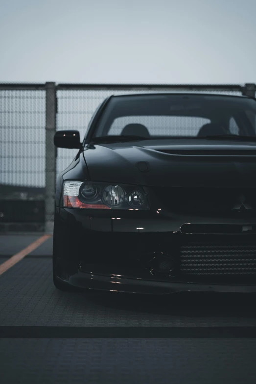 the front view of a black car parked next to a metal fence