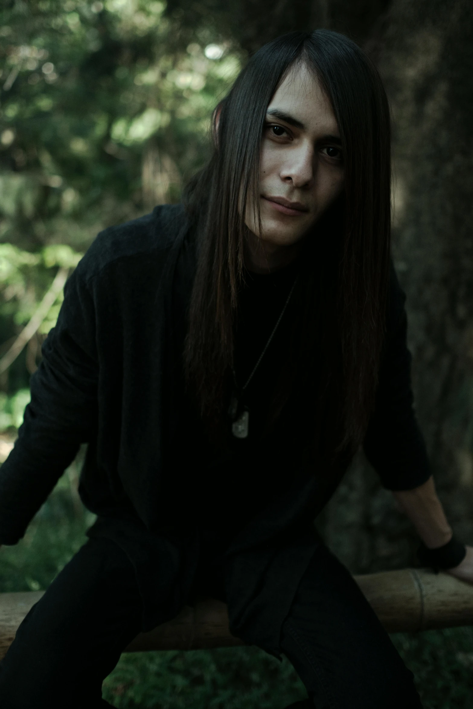 a woman sitting on a wooden post with long hair