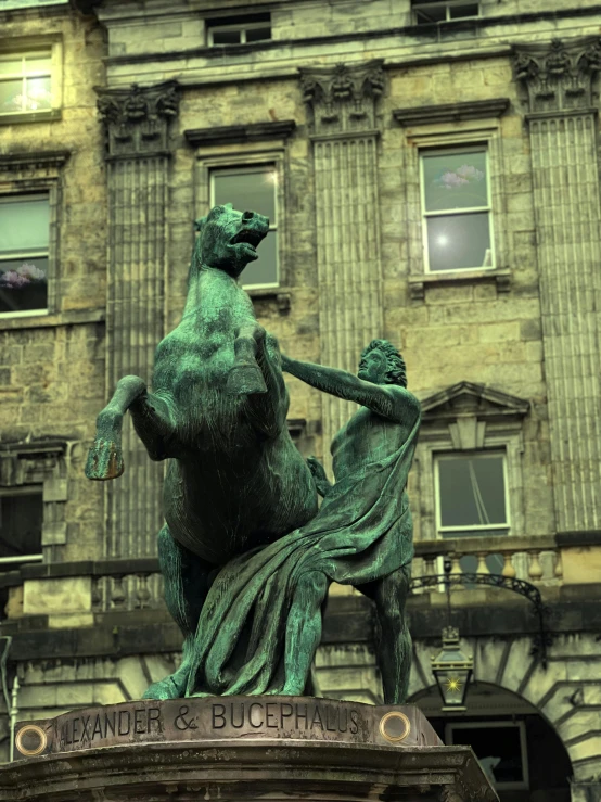 a bronze statue sitting next to a tall building