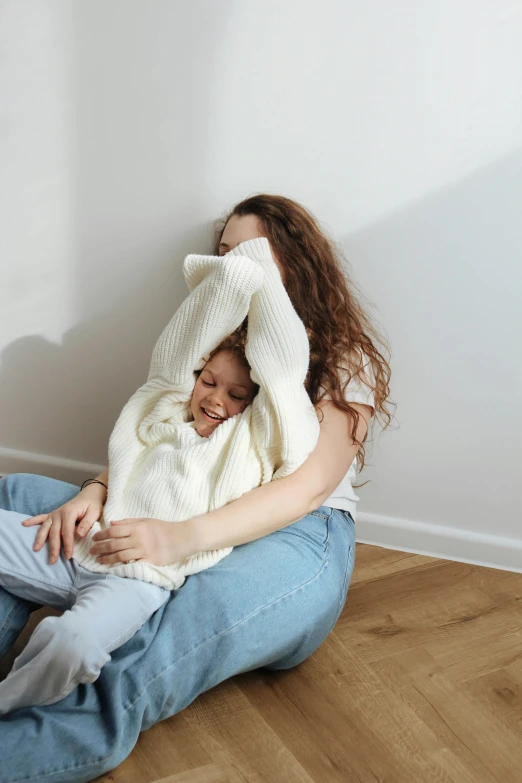 a woman holds a child, who is sitting down