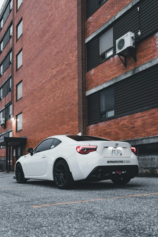 a white sports car is sitting on a grey parking lot