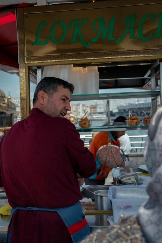 a man wearing a burgundy robe standing in front of a food truck