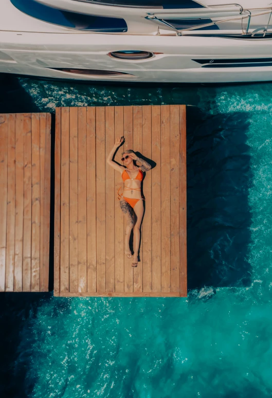 a woman in an orange bikini on a wooden platform