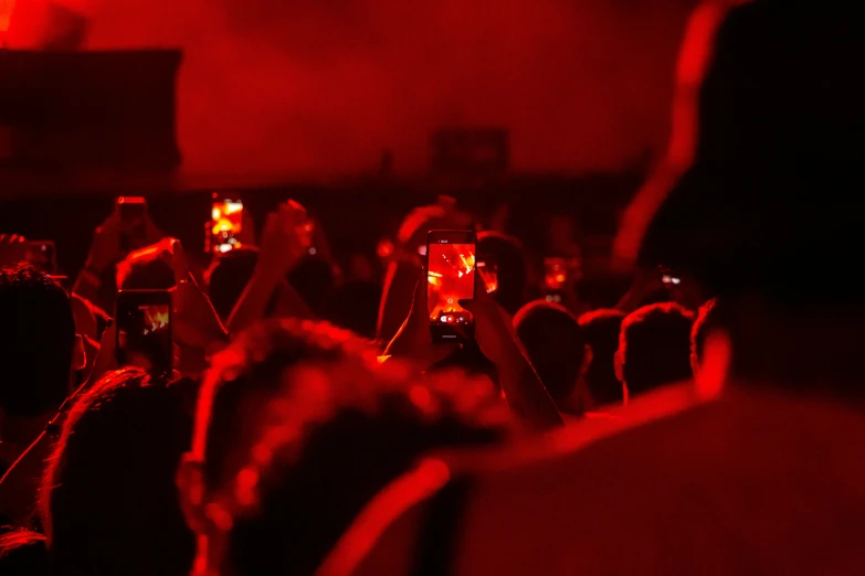 a group of people standing around taking pictures with their cell phones