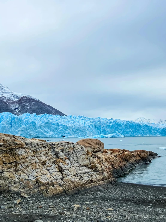 a large snow covered mountain is next to some water