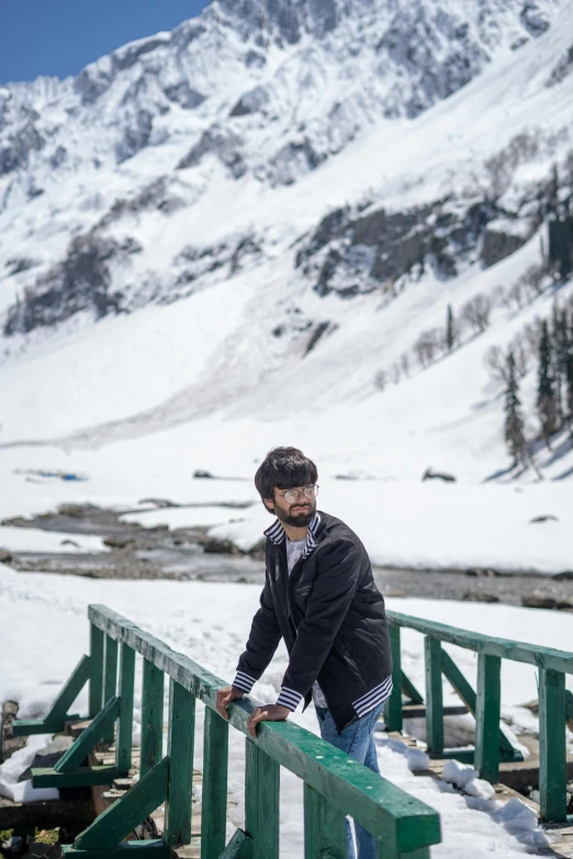 man standing on snowy platform over water and snow covered mountains