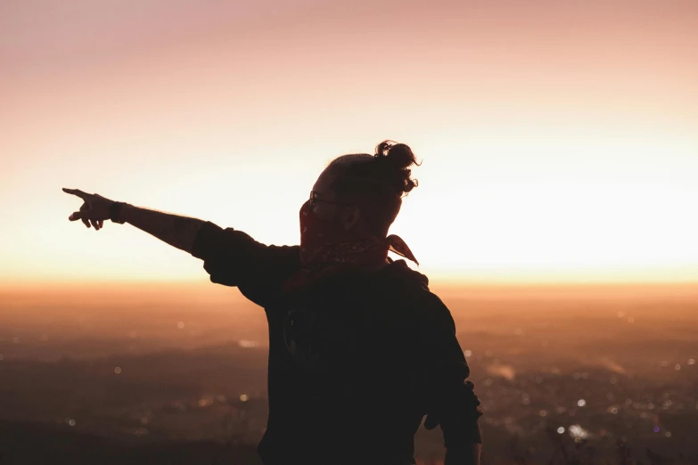 a person looking down at a city with the sun in the background