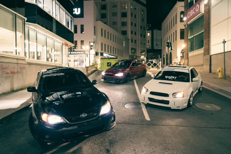 three vehicles parked in a parking lot at night