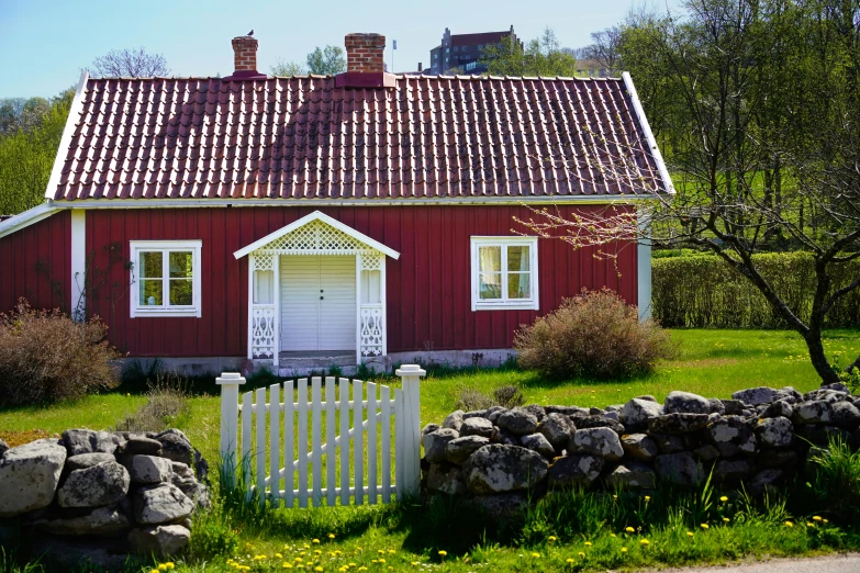 a red house is on a field next to a fence