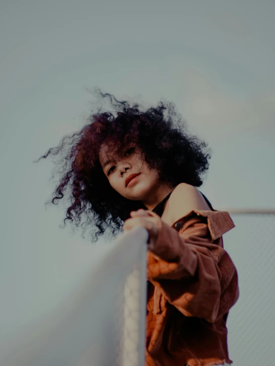 a woman with long hair is standing on a fence