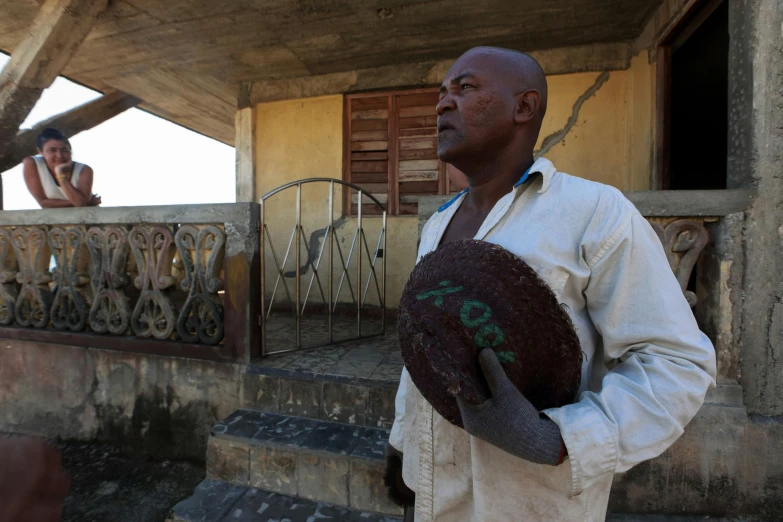 a man stands holding a piece of cake and looking off into the distance