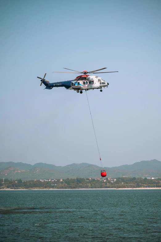 helicopter using a tug rope and an orange ball in the ocean