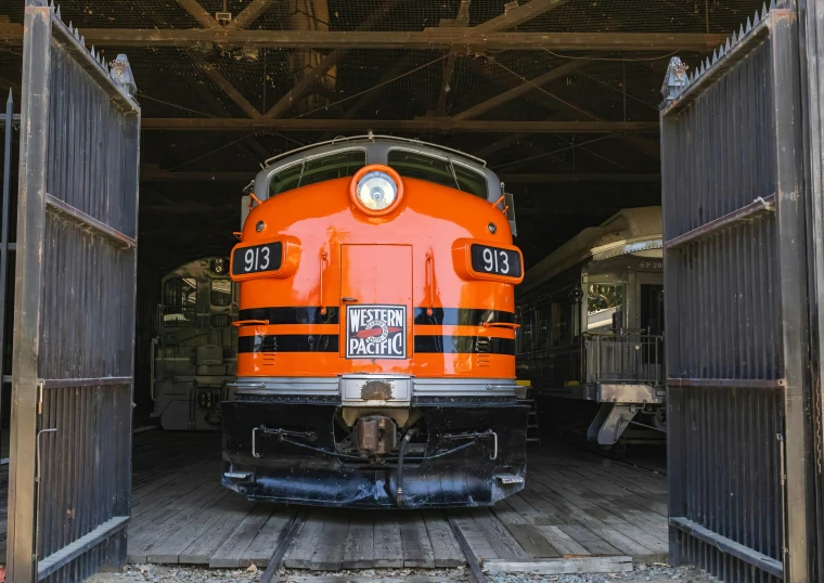 an orange train sits inside a carriage type structure