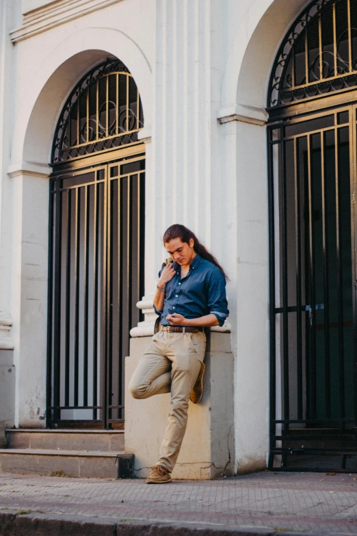 a man on the phone leaning against a building with two doors