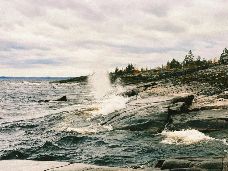 a boat sails away from the rocky shore of a lake