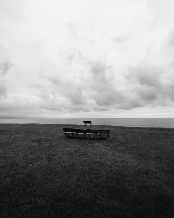 a empty bench on a cloudy day near the ocean